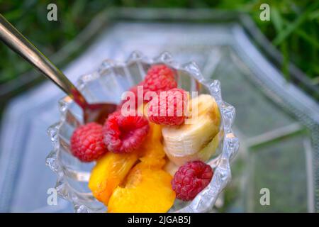 fruits , banane, framboise et pêche dans un bol en verre . Banque D'Images