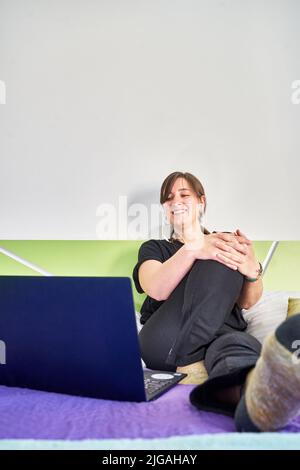 Photo verticale d'une femme souriante caucasienne regardant l'ordinateur de la chambre Banque D'Images