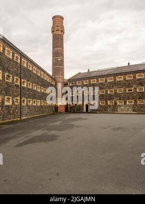 Deux des ailes avec la grande cheminée centrale de l'autre côté de la cour d'exercice de Crumlin Road prison expérience Banque D'Images