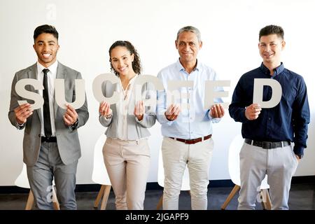 Votre succès est entre vos mains. Un groupe de gens d'affaires tenant des lettres qui orthographont un mot dans un bureau au travail. Banque D'Images