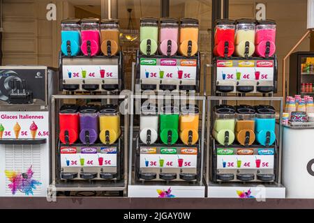 Une glace molle aux couleurs vives remplit six distributeurs sur un stand de rue à Montpellier, en France. Les panneaux de prix indiquent de 3 à 5 euros selon la taille, tandis que des cônes de glace italienne classiques sont également proposés pour 3 à 6,50 euros. Banque D'Images