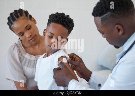 Un jeune médecin de sexe masculin qui a appliqué une balle de coton au bras d'un patient à l'hôpital ne fera pas trop de mal. Banque D'Images