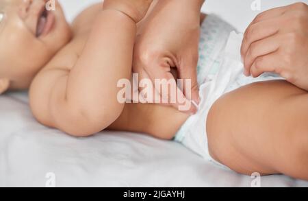 Merci maman. Une femme méconnaissable qui change sa couche de babilys à la maison. Banque D'Images