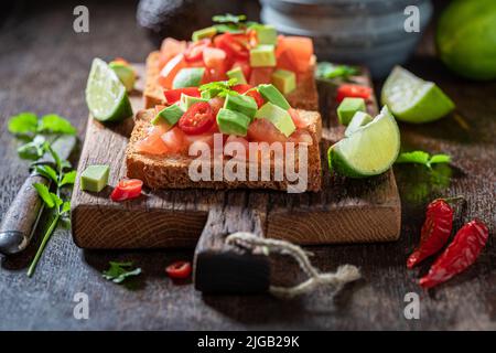 Toasts faits maison et savoureux avec tomates, lime et coriandre. Toasts croquants comme en-cas rapide. Banque D'Images