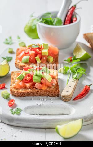 Toasts faits maison et savoureux avec avocat, tomates et coriandre. Toasts croquants comme en-cas rapide. Banque D'Images