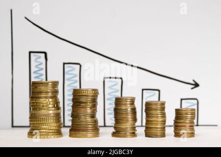 Les pièces sont empilées avec le graphique de récession économique en arrière-plan. Flèche noire indiquant un mouvement vers le bas Banque D'Images