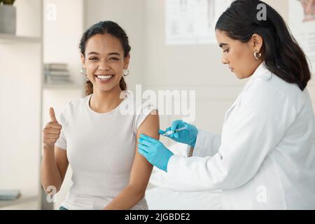Ce n'est pas aussi mauvais qu'il semble. Un jeune médecin attrayant debout et s'injectant sa patiente pendant une consultation dans la clinique. Banque D'Images