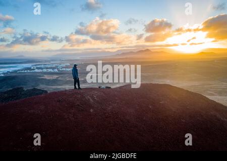homme debout sur le volcan enyoing lanzarote paysage pendant le lever du soleil Banque D'Images
