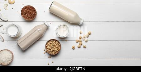 Différentes laits végétaliens sur fond de bois blanc avec espace pour le texte Banque D'Images