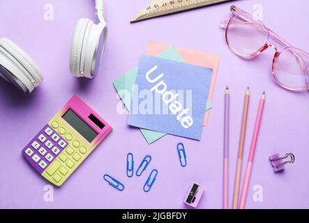 Calculatrice, écouteurs, papeterie et papier avec MISE À JOUR du texte sur fond lilas Banque D'Images