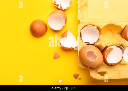 Support en carton avec coquilles d'œufs cassées sur fond jaune, gros plan Banque D'Images