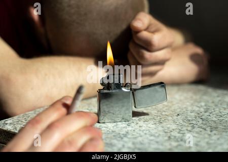 L'allume-cigare brûle sur la table. Feu en arrière-plan de type endormi. Détails de la partie. Fumer est nocif pour la santé. Banque D'Images