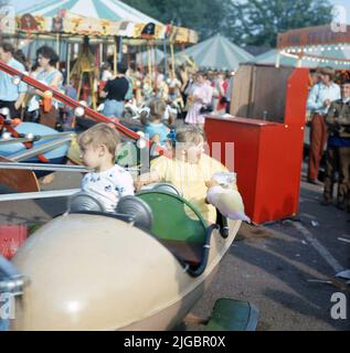 1970s, historique, enfants sur une promenade d'amusement à un parc d'expositions, une jeune fille assis sur la promenade tenant sa soie de bonbons, Angleterre, Royaume-Uni Banque D'Images