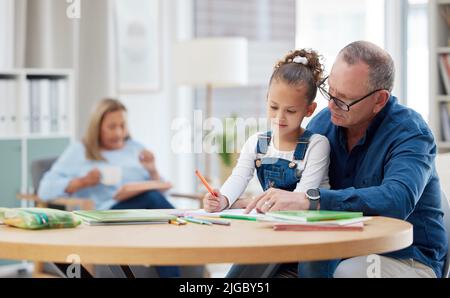 Faire de l'éducation une priorité. Un grand-père aidant son petit-enfant avec ses devoirs à la maison. Banque D'Images