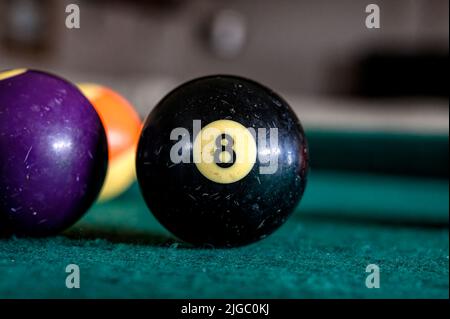 Boule de billard noire avec le numéro 8 sur une table de billard verte avec d'autres boules à proximité. Banque D'Images