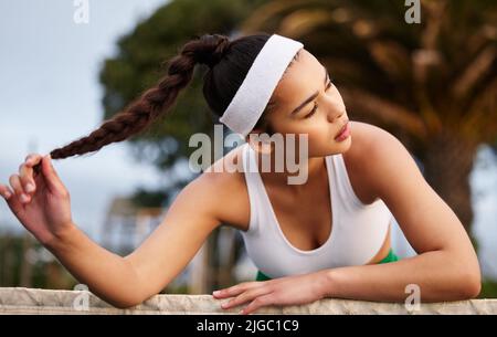 Je rejoue mon match encore et encore dans mes cheveux. Une jeune femme sportive penchée sur le filet de tennis. Banque D'Images