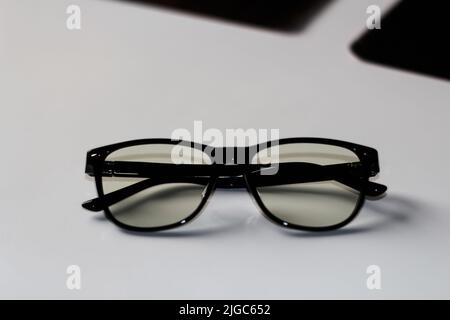 Flou artistique des lunettes noires sur fond blanc. Flat lay, vue de dessus. Une paire de lunettes à rebord foncé vues de l'avant, avec les temples ouverts. Myopie. Banque D'Images