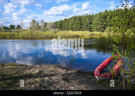 Kayak gonflable rouge près de la rive de la rivière forestière. Promenade printanière jusqu'au parc national. Banque D'Images