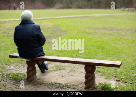 Une femme est assise sur un banc dans le parc. Pensionné en Russie reste dans le parc. Homme sur banc en bois. Banque D'Images