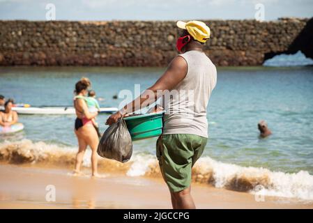 Des vendeurs de rue marchent sur le sable de la plage de Porto da Barra à Salvador, Bahia. Banque D'Images