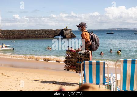 Des vendeurs de rue marchent sur le sable de la plage de Porto da Barra à Salvador, Bahia. Banque D'Images