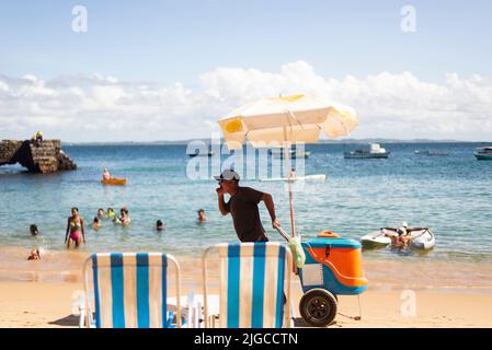 Des vendeurs de rue marchent sur le sable de la plage de Porto da Barra à Salvador, Bahia. Banque D'Images