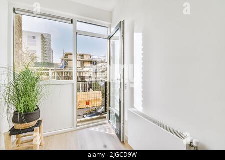 Cette chambre lumineuse dispose d''un pot de fleurs près de la fenêtre et d''une porte-balcon ouverte par temps ensoleillé Banque D'Images