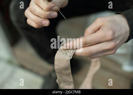 Ruban à coudre. Surpiqûres sur le col dans l'armée. Travail de weaver. Réparer les vêtements avec vos propres mains. Banque D'Images