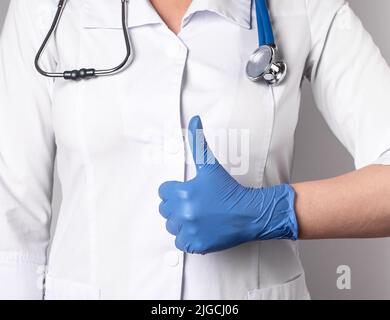 Médecin avec le pouce vers le haut. Bonne santé, confiance dans le concept de compétence professionnelle médicale. Femme en blouse de laboratoire et en gants montrant le panneau d'approbation avec la main. Photo de haute qualité Banque D'Images