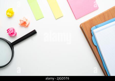 Vue de dessus de notes adhésives colorées, d'un bureau et d'une loupe sur fond blanc Banque D'Images