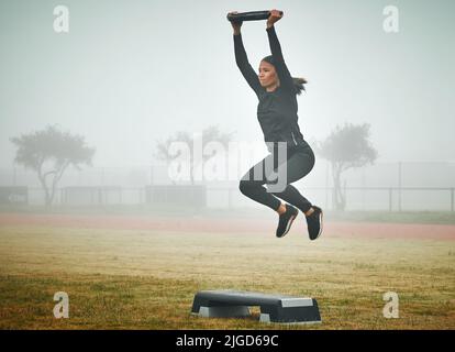 Continuez à vous entraîner comme une femme sportive qui fait de l'exercice sur un pas avec une plaque de musculation à l'extérieur. Banque D'Images