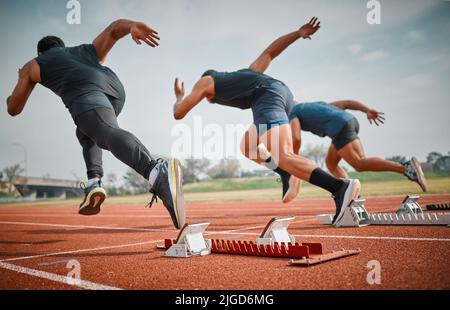 Et c'est tout. Photo en vue arrière de trois jeunes athlètes masculins méconnus qui débutent leur course sur une piste. Banque D'Images