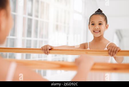 Rêve grand, danse plus grand. Une petite fille pratiquant le ballet dans un studio de danse. Banque D'Images