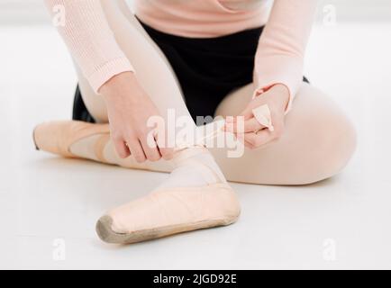 Une chaussure ample donne une performance désordonnée. Une danseuse de ballet méconnaissable qui s'adapte à ses chaussures avant l'entraînement. Banque D'Images