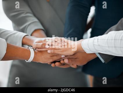 Allons en équipe. Un groupe d'hommes d'affaires méconnus debout au bureau avec leurs mains dans un caucus. Banque D'Images