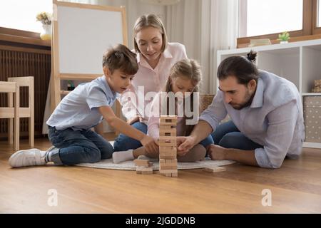 Parents motivés et deux petits enfants jouant à un jeu de société Banque D'Images