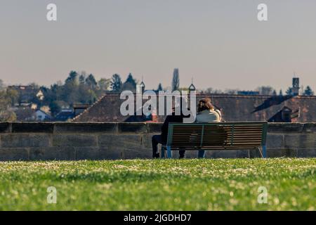 Un couple assis sur un banc dans un parc qui regarde le village Banque D'Images