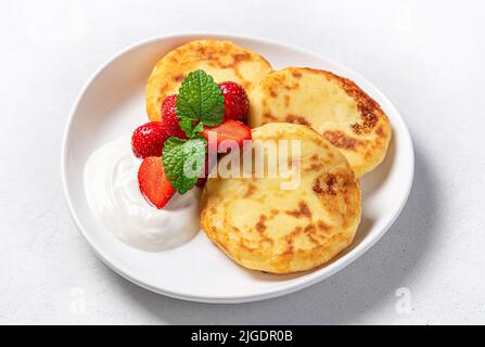 Crêpes au fromage cottage avec fraises sur fond gris. Banque D'Images