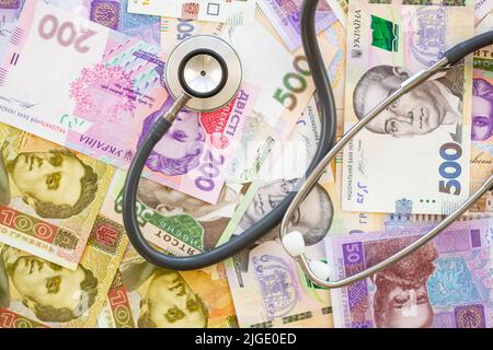 Stéthoscope et argent. Le concept de la médecine coûteuse. Hryvnia ukrainien. Beaucoup de billets de banque sur la table. Beaucoup d'argent en arrière-plan. Santé Banque D'Images