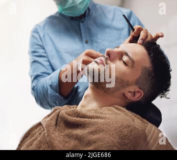 Il s'est taillé les cheveux et la barbe. Un beau jeune homme s'est entretenu par un barbier. Banque D'Images