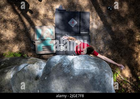 Le jeune homme sportif saute pour le coup de tête dans le célèbre et dur problème de bloc dyno appelé 'Cannon ball -7b'. Fontainbleau, France, Europe. Banque D'Images