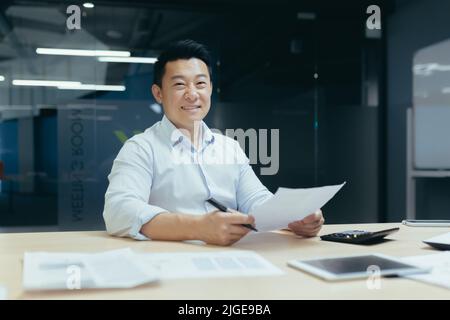 Portrait d'un homme d'affaires asiatique réussi, homme souriant et regardant la caméra, courtier faisant des formalités administratives Banque D'Images