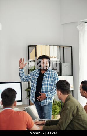 Un fondateur de la start-up enthousiaste qui parle devant une équipe de développeurs et de responsables au bureau Banque D'Images