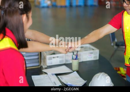 Unité et travail d'équipe. Une équipe de travailleurs asiatiques se tenant ensemble et se tenant à la main avant de travailler dans l'entrepôt. Banque D'Images