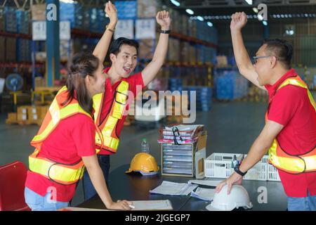 Unité et travail d'équipe. L'équipe de travailleurs asiatiques se tenant debout et se lève la main avant de travailler dans l'entrepôt. Banque D'Images