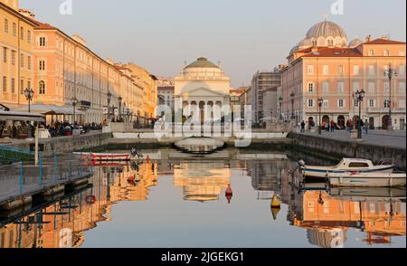 TRIESTE, Italie - 25 mars 2022: La vie sur le Canal Grande au coucher du soleil avec la Piazza Sant'Antonio et l'église néo-classique du même nom en arrière-plan Banque D'Images