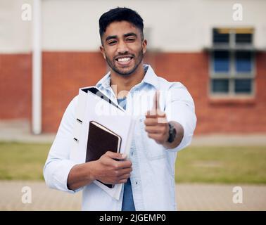 Avec la patience et la persévérance, vous pouvez passer aussi. Un jeune homme montrant les pouces vers le haut tout en se tenant à l'extérieur à l'université. Banque D'Images