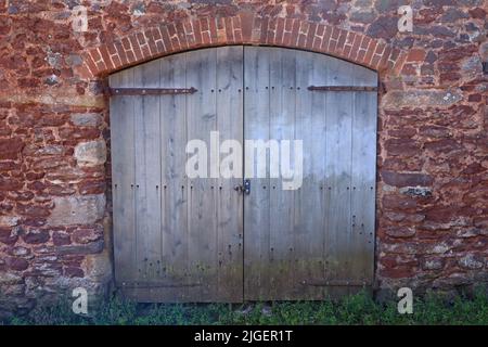 Vieilles portes doubles brunes avec un haut voûté sur une grange à Dunster dans Somerset, Angleterre Banque D'Images