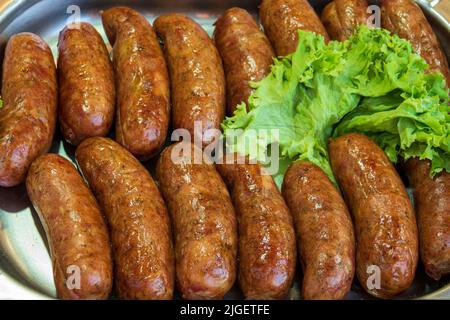 De savoureuses saucisses barbecue avec salade sur la poêle. Banque D'Images