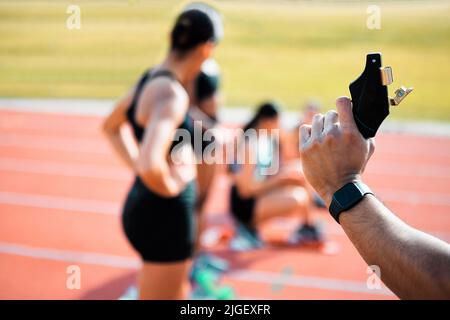 Essayer des préparer. Vue arrière d'un homme méconnaissable tenant un pistolet de démarrage alors qu'un groupe de sportifs prend leurs positions sur la piste. Banque D'Images